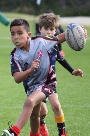 Boy running with rugby ball in rugby game
