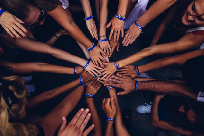 Birds-eye-view of group of event volunteers with hands in together