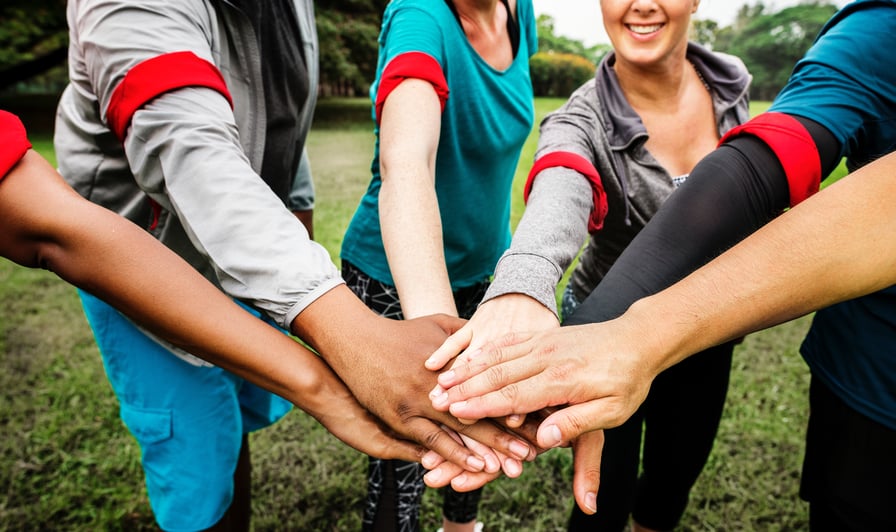 group of people in circle with hands I the middle