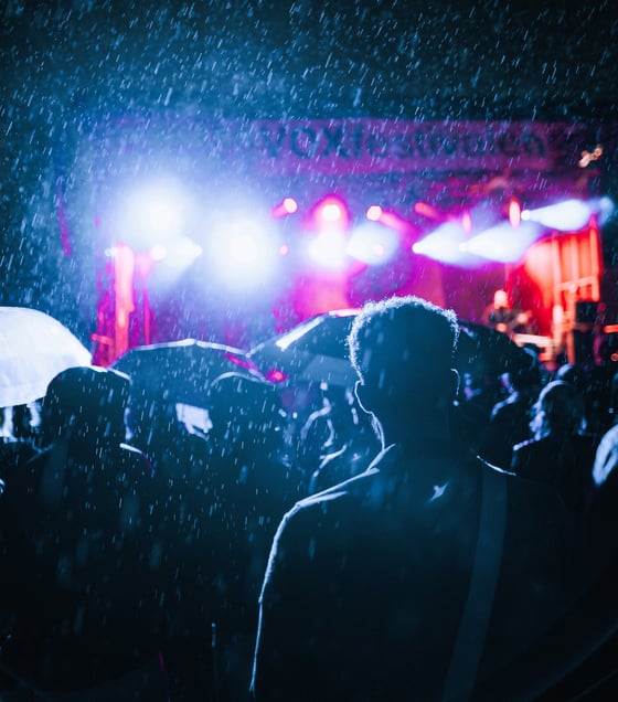 silhouettes of crowd at a festival at night in the rain