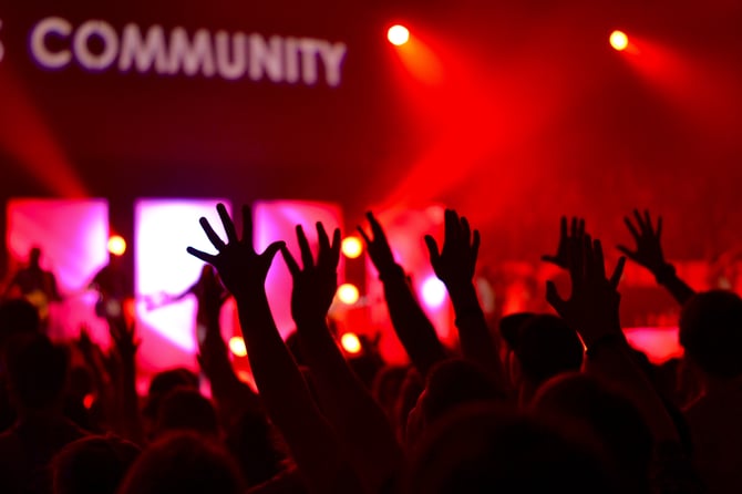 hands in the air at event with the word 'community' lit up